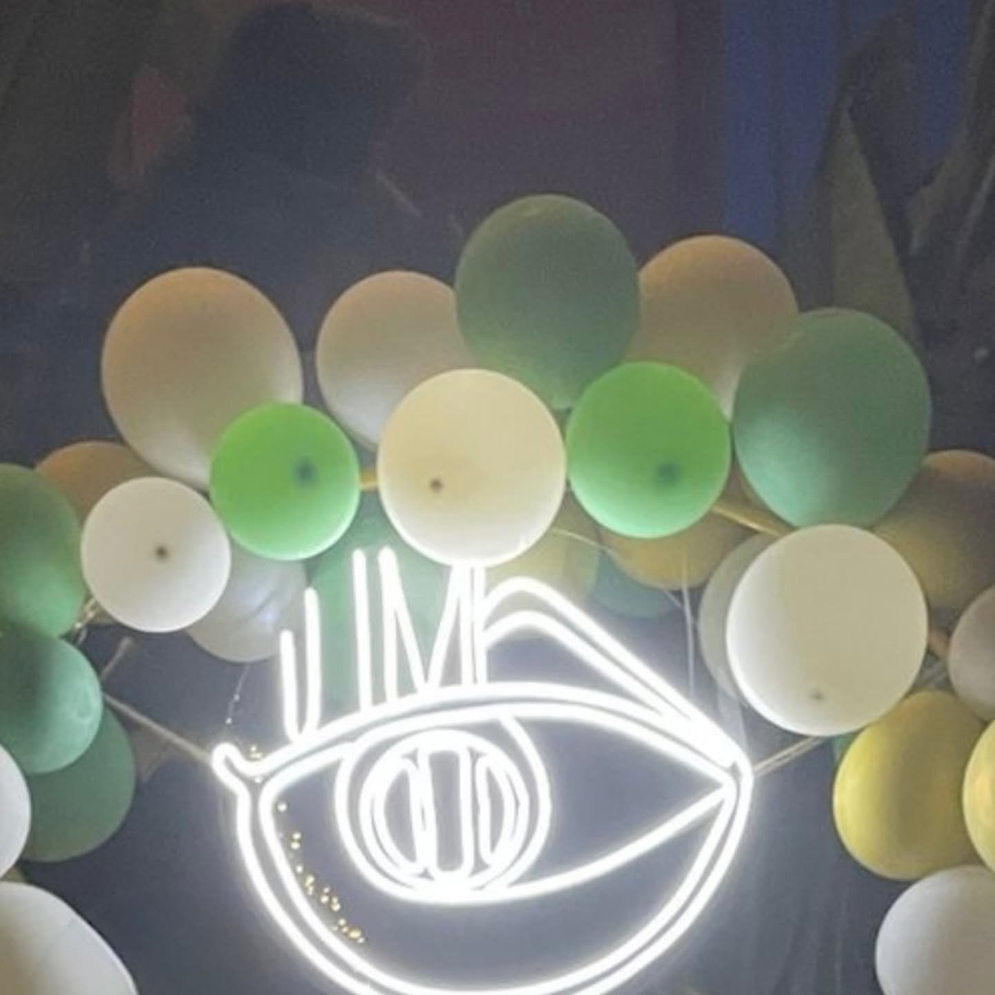 El rótulo de neón de JM Beauty Art, con la forma de un ojo, encendido en la pared del centro
